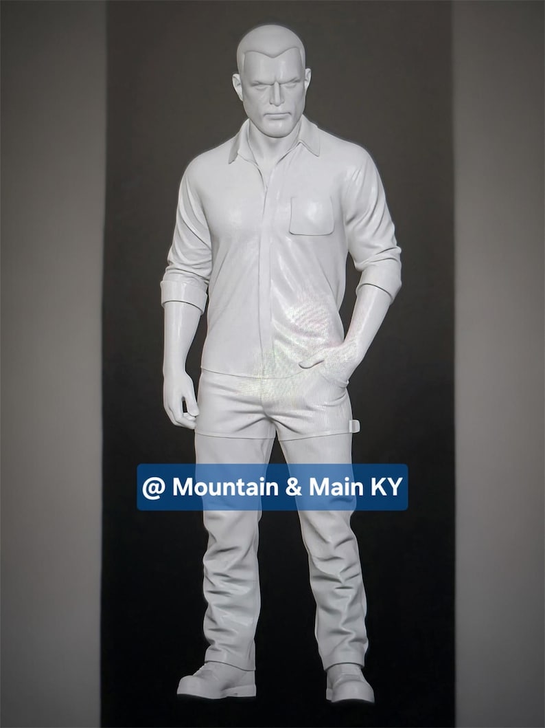May include: A solid white, full-body mannequin of a person with short hair, wearing a button-down shirt with a chest pocket and long pants. The figure stands in a neutral pose with one hand in a pocket. A blue rectangular label displays @ Mountain & Main KY.