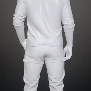 May include: A full-body white mannequin standing in a rear-facing position. The mannequin is wearing a long-sleeved collared shirt with sleeves pushed up to the elbows, paired with fitted trousers that feature a horizontal seam detail at the mid-thigh.