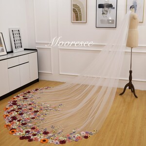 May include: A long white tulle wedding veil with a floral design. The veil is decorated with colorful embroidered flowers, including red, orange, yellow, pink, purple, and blue.
