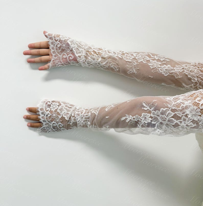 May include: A pair of white lace gloves with a floral pattern. The gloves are long, extending past the elbows, and feature a delicate, openwork design. The lace is detailed and intricate, creating a romantic and elegant appearance.