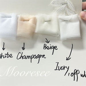 May include: Four swatches of white fabric in different shades: white, champagne, beige, and ivory/off white. The swatches are labeled with their corresponding colors.