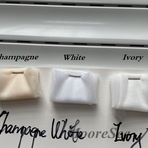 May include: Three fabric swatches labeled "Champagne", "White", and "Ivory". The swatches are arranged from left to right in the order of their labels. The swatches are all white, but the "Champagne" swatch has a slight yellow tint.