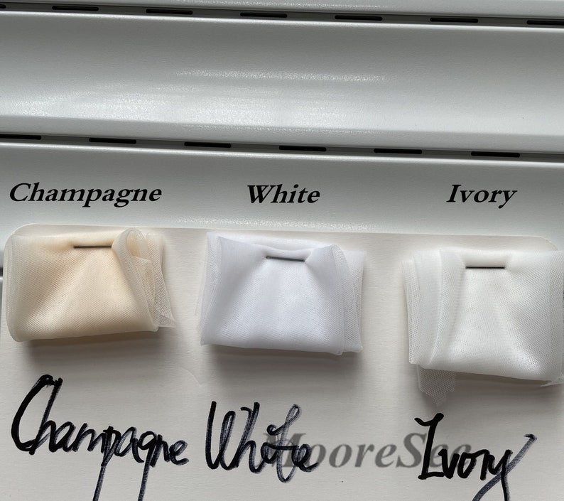 May include: Three fabric swatches labeled "Champagne", "White", and "Ivory". The swatches are arranged from left to right in the order of their labels. The swatches are all white, but the "Champagne" swatch has a slight yellow tint.