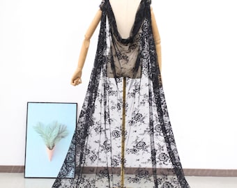 May include: A black lace cape with a floral pattern. The cape is draped over a mannequin and has a long train.