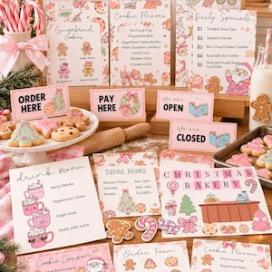 Op de afbeelding: Een Santa's Cookie Shop kerst-rollenspelset met roze en wit bedrukte borden, menu's en bestelformulieren. De set bevat illustraties van peperkoekmannetjes, zuurstokken en kerstlekkernijen met teksten zoals Order Here, Pay Here en Christmas Bakery.