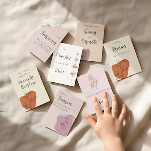 May include: A collection of inspirational cards with various phrases and floral illustrations. The cards feature text like "Inspiring," "Strong and Capable," and "Heavenly Kingdom." The color palette includes soft pinks, creams, and earthy tones.