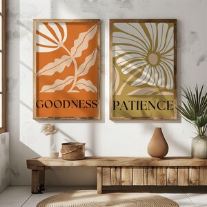 Earth-toned abstract flower art prints labeled “GOODNESS” and “PATIENCE,” framed and displayed in a cozy boho entryway with natural textures and sunlight.