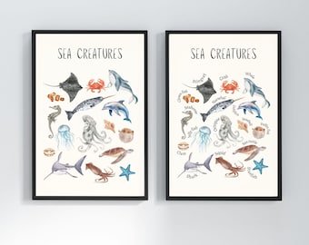 May include: Two framed art prints featuring watercolor illustrations of various sea creatures, including a stingray, crab, and shark. The text "SEA CREATURES" is at the top of each print. The prints are in black frames.
