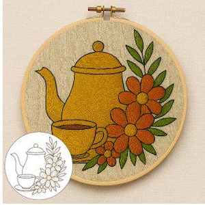 Peut inclure: Broderie d'art sur le thème du thé. Le motif présente une théière jaune, une tasse à thé et des fleurs orange avec des feuilles vertes. L'œuvre est encadrée dans un cercle de tissu beige et un cerceau en bois.