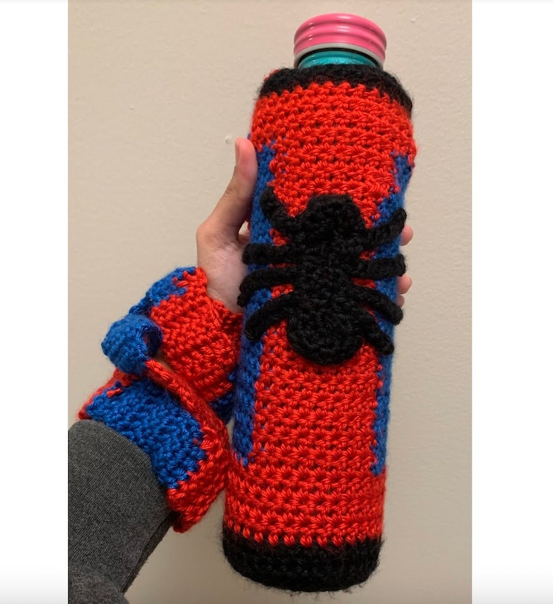May include: Crocheted bottle cover and matching wrist cuffs in red, blue, and black. The bottle cover features a large black spider design. The wrist cuffs have a red and blue color scheme. The bottle cover is designed to fit a standard size bottle.