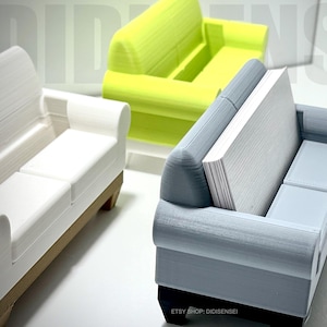 May include: Three miniature couches, one white, one light green, and one gray, are used as business card holders. The gray couch has a stack of business cards in the back.