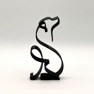 May include: Black metal sculpture of a dog in a sitting position, with a minimalist, continuous line design. The dog's head is raised, and the tail curls around. The sculpture is on a white background.