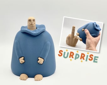 Op de afbeelding: Een blauw 3D-geprint beeldje van een persoon met een verraste uitdrukking. Het beeldje houdt zijn handen voor zijn borst. Het beeldje staat op een wit oppervlak. De tekst "SURPRISE" is zichtbaar op de achtergrond.