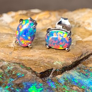 Peut inclure: Une paire de boucles d'oreilles en argent avec des pierres précieuses en opale de forme ovale. Les opales présentent un arc-en-ciel de couleurs, notamment le bleu, le vert, le rouge et l'orange.