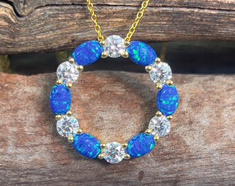 Collar circular de plata chapada en oro con colgante de ópalo azul verdoso creado mediante fuego.