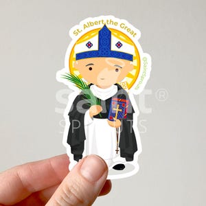 Może przedstawiać: Wykrawana naklejka z rysunkową ilustracją świętego Alberta Wielkiego w niebiesko-białej mitrze i czarno-białym habicie, trzymającego zieloną gałązkę palmową oraz niebieską księgę ze złotym krzyżem. Nad postacią znajduje się łukowaty napis St. Albert the Great.