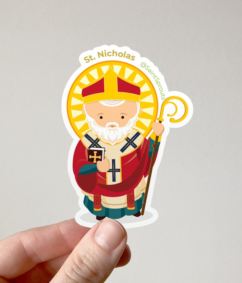 May include: A sticker featuring a cartoon illustration of Saint Nicholas, a white-bearded man wearing a red and gold bishop's robe, holding a book and a staff. The sticker has a yellow halo and the text "St. Nicholas @SaintSprouts" around the border.