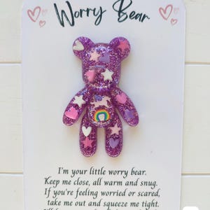 May include: Purple glitter worry bear with pink hearts and stars. The bear has a rainbow on its chest. The card reads "Worry Bear" and "I'm your little worry bear. Keep me close, all warm and snug. If you're feeling worried or scared, take me out and squeeze me tight. I'll keep you safe all day and night."