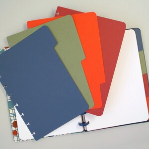 Könnte beinhalten: Ein Satz bunter Trennblätter für einen Ringbuchplaner. Die Trennblätter sind in den Farben Blau, Grün, Orange und Rot gehalten. Die Trennblätter sind für einen Standard-Ringbuchplaner konzipiert.