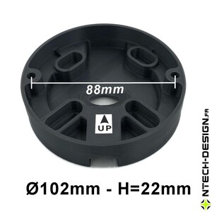 Op de afbeelding: Zwart cirkelvormig onderdeel met een centrale opening en meerdere verzonken secties. De diameter is 102 mm, de hoogte is 22 mm en de interne diameter is 88 mm. De tekst "UP" en een pijltje zijn zichtbaar.
