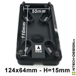 Può includere: Un componente rettangolare nero con quattro fori di montaggio e quattro bulloni. Le dimensioni sono 124 mm x 64 mm, con un'altezza di 15 mm. La parte superiore ha un elemento circolare in gomma e una freccia "UP". La parte superiore misura 50 mm x 110 mm.