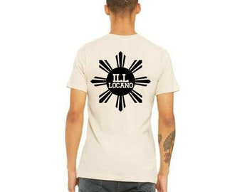 May include: A beige t-shirt with a black graphic of a sun with eight rays and the text "ILL LOCANO" inside the sun.