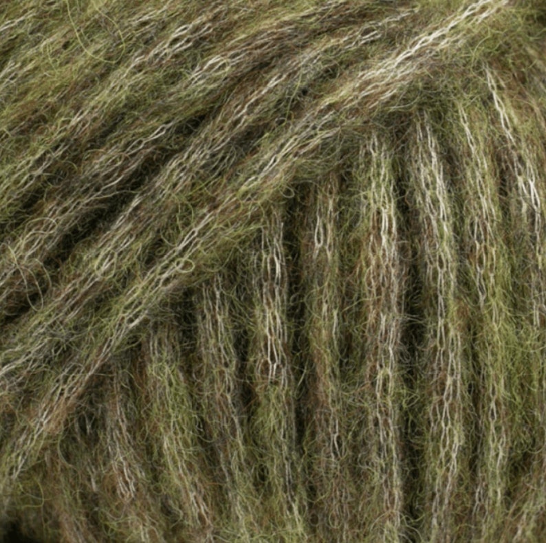 May include: Close-up of a skein of green and white yarn. The yarn is soft and fluffy, with a subtle sheen.