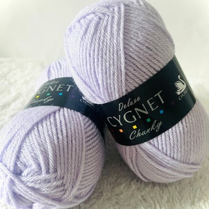 May include: Two balls of light purple yarn labeled "Deluxe Cygnet Chunky" yarn.