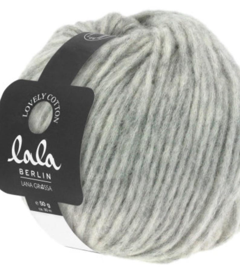 May include: A ball of gray and white yarn with a black label that reads "lala BERLIN LANA GRASSA 50 g"