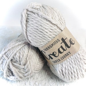 Puede incluir: Dos ovillos de hilo supergrueso de color gris claro con una etiqueta marrón que dice "Create Yarnsmiths Super Chunky".