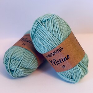 May include: Two balls of light green yarn with a brown label that reads "Yarnsmiths Merino DK".