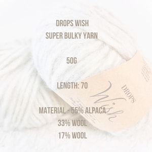 May include: A ball of white Drops Wish Super Bulky yarn with a brown label that reads "Drops Wish" and lists the yarn's composition as 55% alpaca, 33% wool, and 17% wool. The label also states that the yarn weighs 50 grams and has a length of 70 meters.
