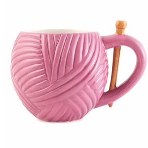 Peut inclure: Une tasse en céramique rose en forme de pelote de laine avec une poignée en aiguille à tricoter marron.