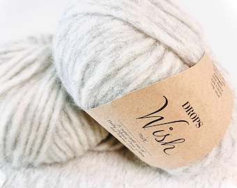 May include: Two skeins of DROPS Wish yarn in a light gray color. The yarn is a blend of baby alpaca, cotton, and wool. The label reads "DROPS Wish mix A super soft mix of Baby Alpaca, Puma, Cotton and Wool."