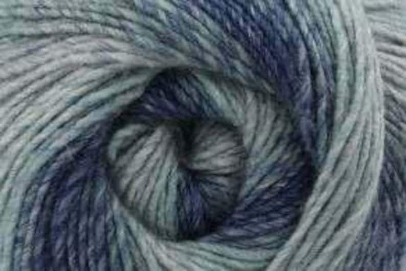 May include: Close-up of a ball of yarn in shades of blue, teal, and gray. The yarn is tightly wound, revealing a spiral pattern. The texture appears soft and slightly fuzzy, suggesting a blend of natural fibers.