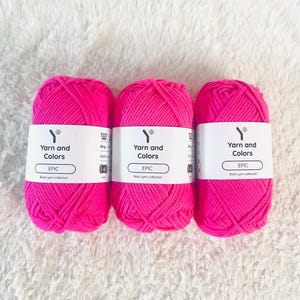 May include: Three pink yarn balls labelled "Yarn and Colors EPIC Basic yarn collection" with a white label and a white washing instruction icon.