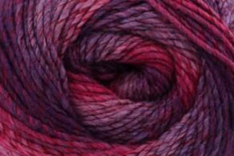 May include: Close-up of a ball of yarn in shades of purple, magenta, and red. The yarn appears to be a blend of colors, creating a textured and visually appealing effect. The fibers are tightly wound, suggesting a durable and high-quality material suitable for knitting or crocheting projects.