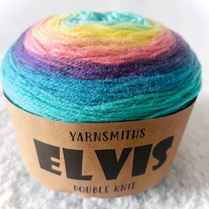 May include: A ball of multi-colored yarn with a rainbow gradient of colors, including teal, blue, purple, pink, yellow, and green. The yarn is wrapped in a brown paper label that reads "YARNSMITHS ELVIS DOUBLE KNIT."