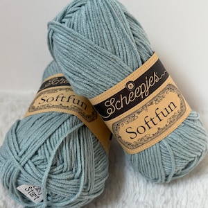 May include: Two balls of light blue Scheepjes Softfun yarn. Each ball has a brown label with the brand name and product details. The yarn is soft and appears to be a cotton blend, suitable for knitting or crochet projects.