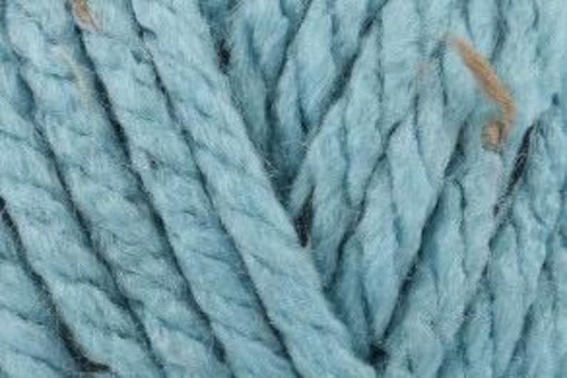 Peut inclure: Une pelote de fil bleu clair avec une texture duveteuse. Le fil est compos&eacute; d'un m&eacute;lange de fibres, dont le coton et la laine.