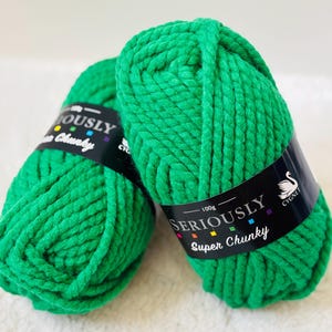 Könnte beinhalten: Zwei Knäuel leuchtend grüne, super dicke Wolle. Jedes Knäuel hat ein schwarzes Etikett mit der Aufschrift "SERIOUSLY Super Chunky" und "100g". Die Wolle ist ein dickes, strukturiertes Material, ideal zum Stricken.