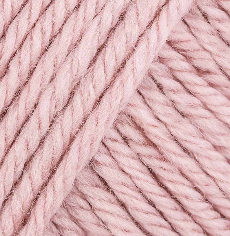 May include: Close-up of a soft, pink yarn skein. The yarn is made of natural fibers and has a fuzzy texture.