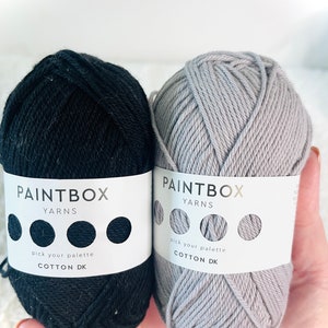 May include: Two balls of cotton yarn, one black and one gray. The yarn is labeled "Paintbox Yarns Cotton DK" and has a color palette selector.