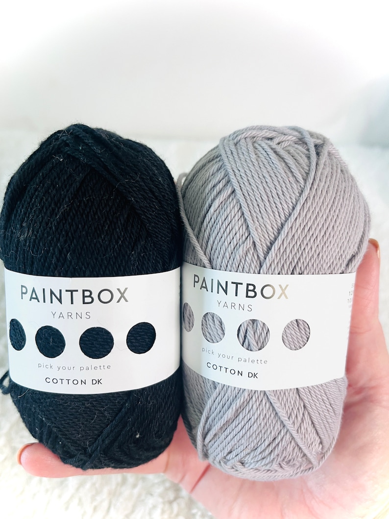 May include: Two balls of cotton yarn, one black and one gray. The yarn is labeled "Paintbox Yarns Cotton DK" and has a color palette selector.