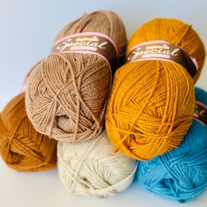 May include: A collection of yarn skeins in various colors, including brown, mustard yellow, cream, and teal. Each skein is wrapped with a band that reads "Special". The yarn is tightly wound, suggesting it is for knitting or crochet projects.