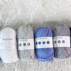 May include: Six balls of yarn in different colors: light blue, white, light gray, lavender, gray, and black. Each ball has a white label with the text "PAINTBOX YARNS" and "COTTON DK".