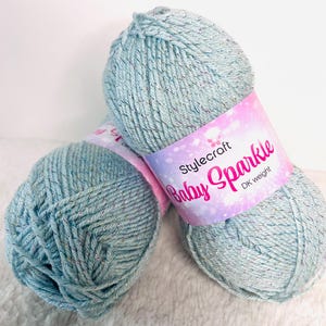 May include: Two skeins of light blue yarn with silver glitter. The yarn is labeled "Stylecraft Baby Sparkle DK weight."