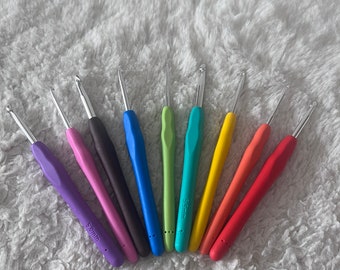 May include: A set of nine colorful crochet hooks, arranged in a rainbow pattern. The hooks are made of plastic and have a smooth, comfortable grip. The sizes of the hooks are labeled in millimeters.
