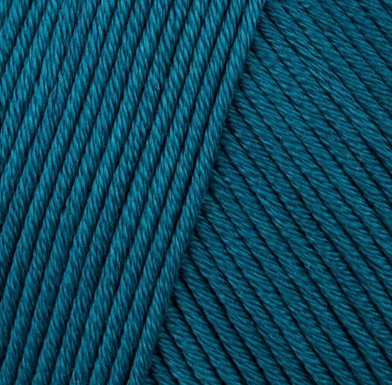 May include: Close-up of teal blue yarn. The yarn is soft and textured, with a subtle sheen.