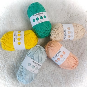 May include: Five balls of yarn in different colours: green, yellow, beige, peach, and light blue. Each ball has a white label with the text "PAINTBOX YARNS" and "COTTON DK".